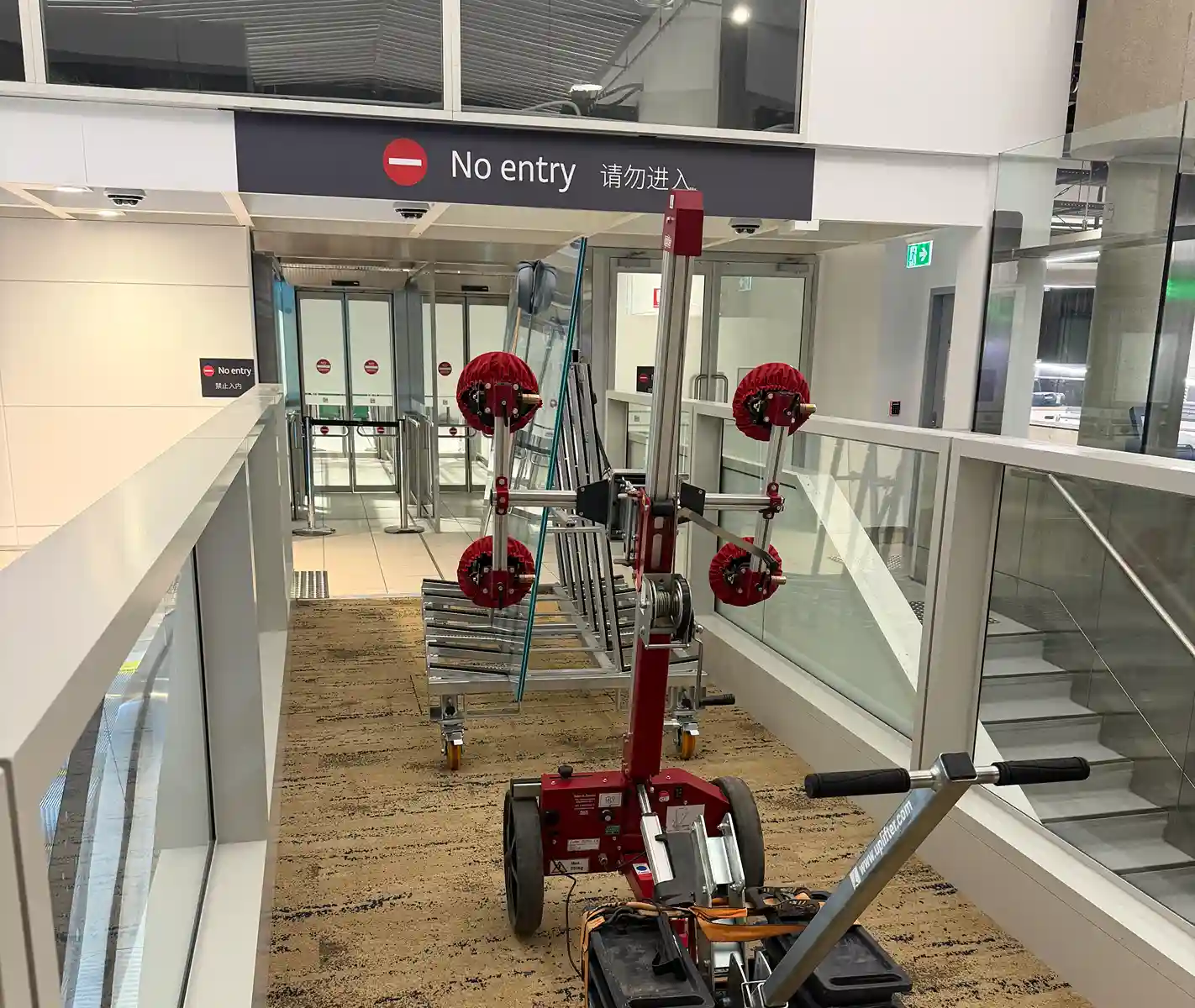 Glass installation equipment positioned beside airport terminal glazing.